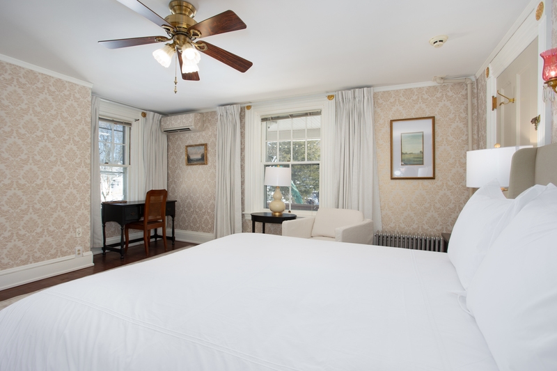 spacious room with queen bed, armchair, wardrobe, ceiling fan