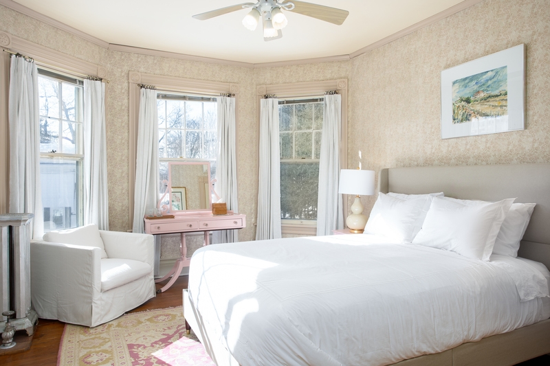 plush bed in a room featuring pink vanity and large windows