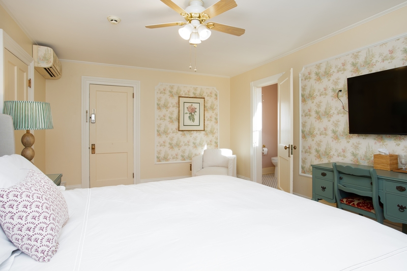 king bed with side tables and lamps, cozy blue rug, and green accents