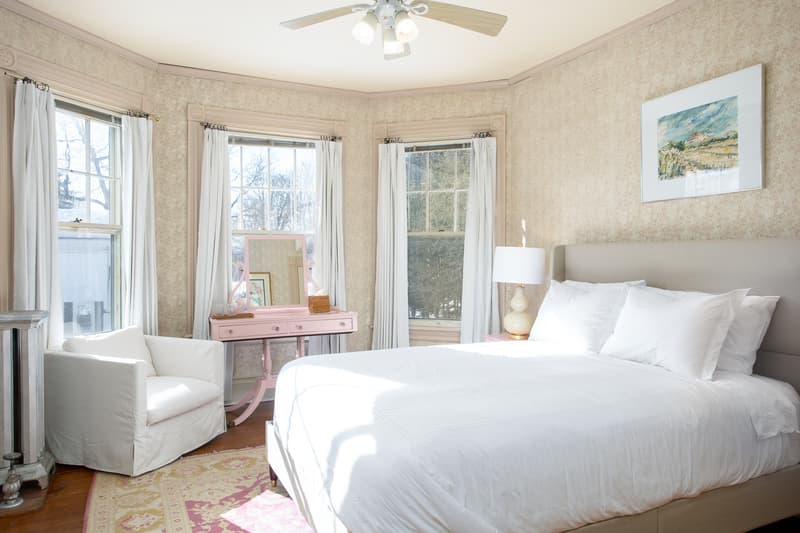 plush bed in a room featuring pink vanity and large windows