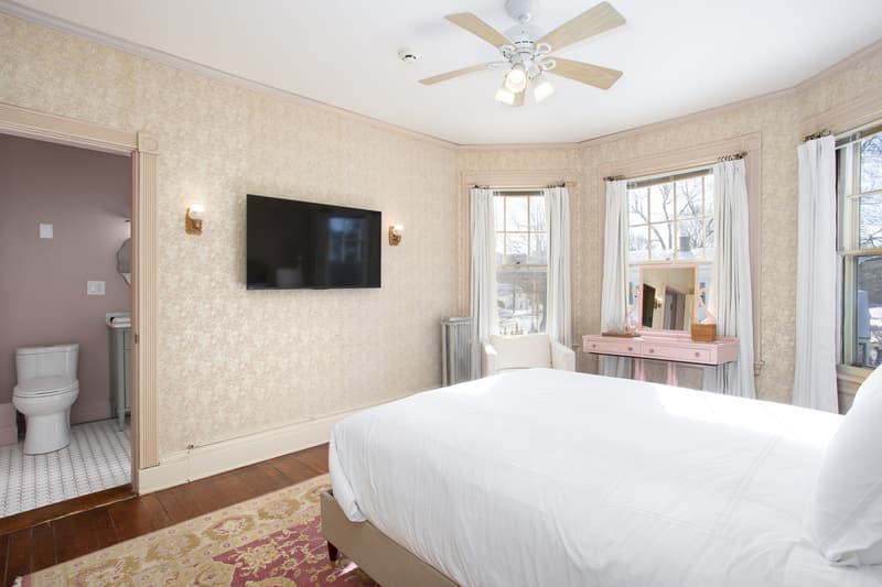 queen sized bed with plush bedding and pink accents in room