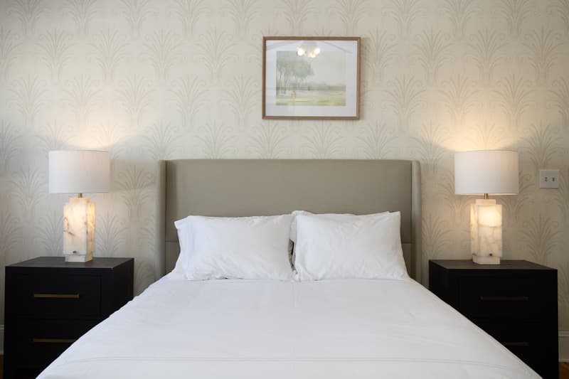 spacious suite with plush bed, large windows, desk, pink rug