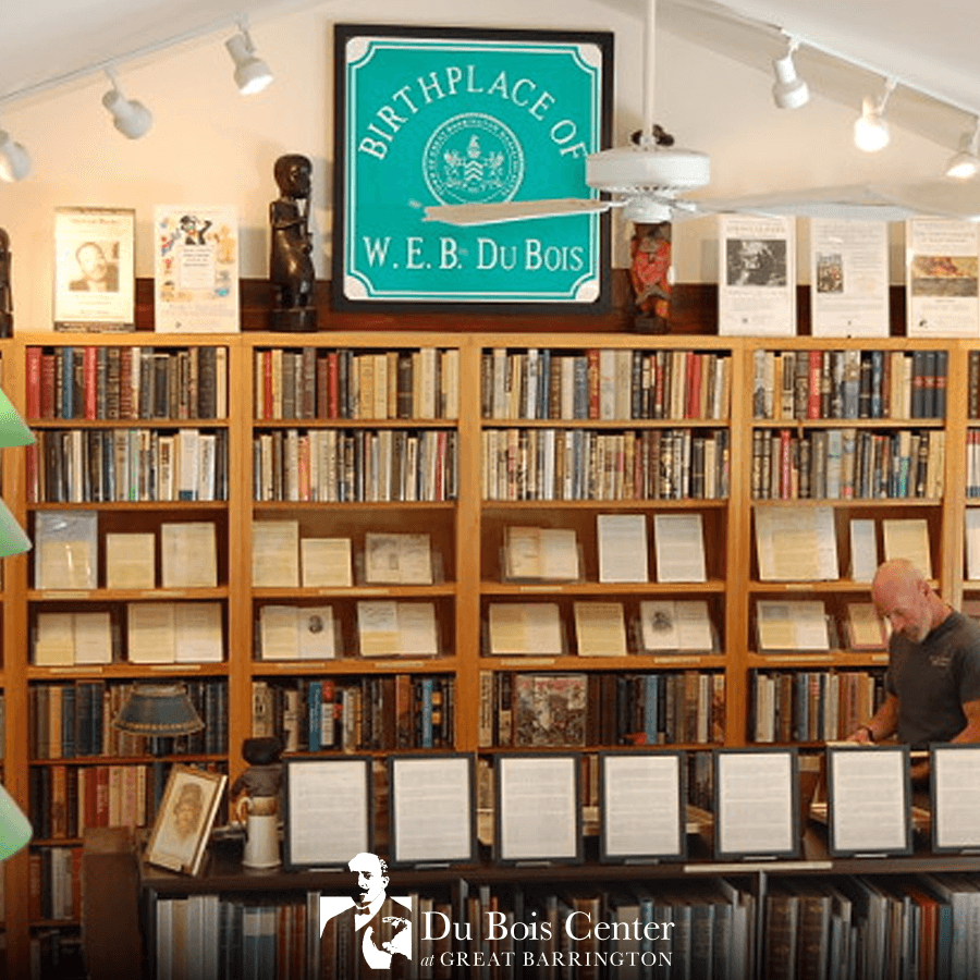 A person browsing a bookshelf filled with books and historical displays at the W.E.B. Du Bois birthplace.