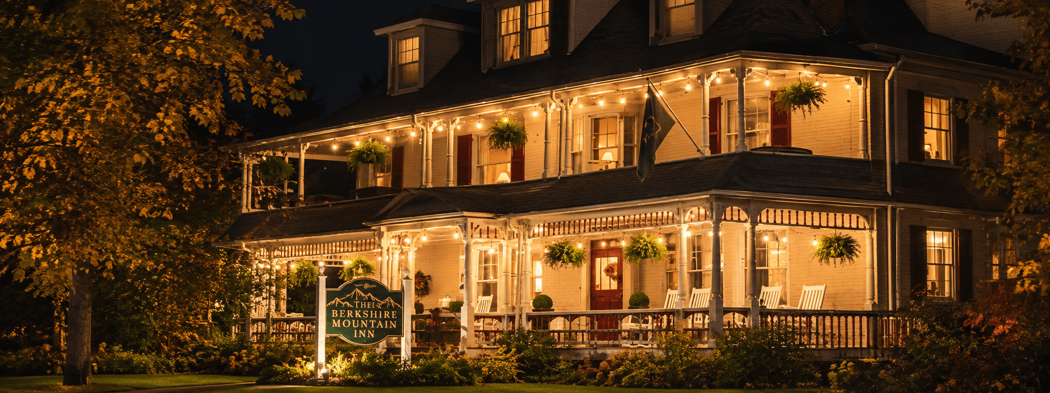 A charming inn illuminated at night with warm lights and surrounding greenery.