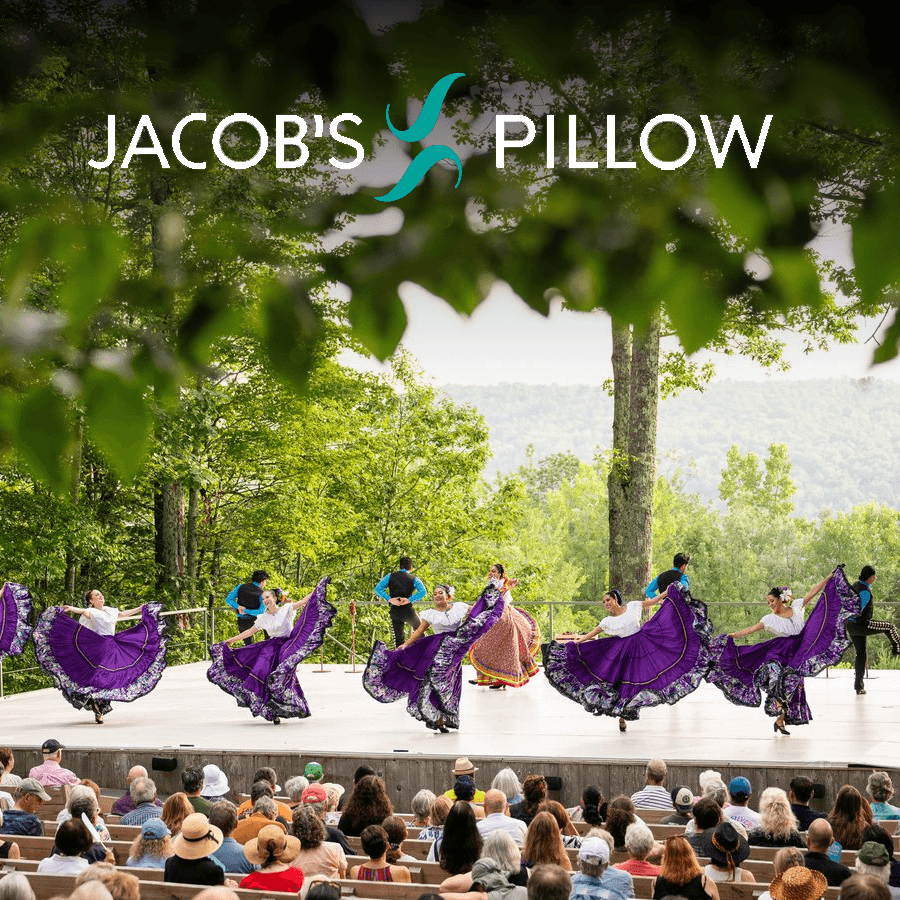 A vibrant dance performance takes place outdoors at Jacob's Pillow, surrounded by an audience and lush trees.