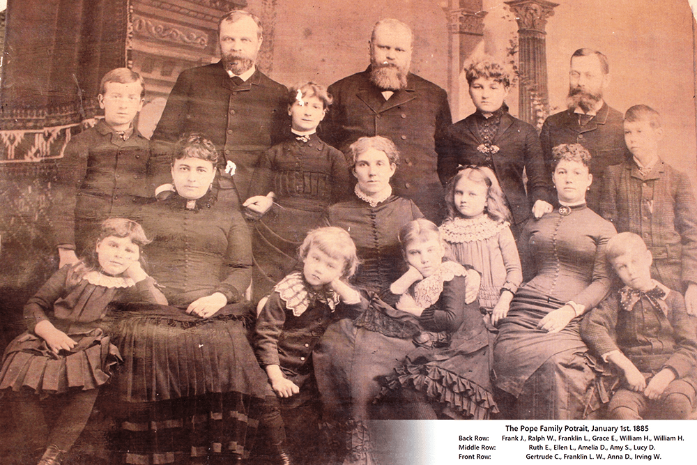 A large group of 19th-century individuals poses together in formal attire for a family portrait.