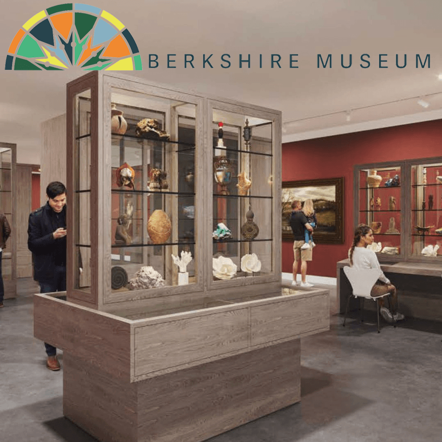 Interior view of the Berkshire Museum showcasing display cases filled with various artifacts and visitors engaging with the exhibits.