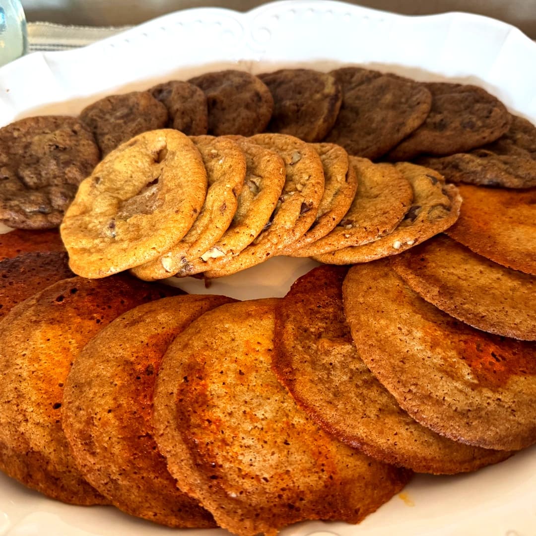 A platter of various cookies, including golden and dark chocolate chip varieties, arranged in a circular display.