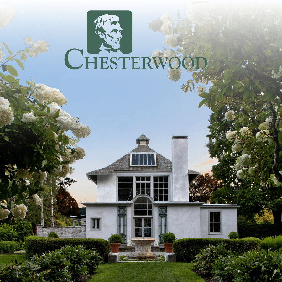 A modern white house surrounded by lush greenery and flowers, with "Chesterwood" branding above.